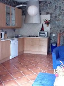 a kitchen with a tile floor and a blue couch at 2 bedrooms house with enclosed garden and wifi at Aljezur 8 km away from the beach in Aljezur