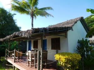 a small white house with a palm tree at 2 bedrooms bungalow with sea view shared pool and enclosed garden at Andilana in Andilana