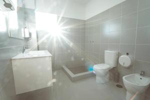 a white bathroom with a toilet and a sink at Modern apartment in Estói with shared pool. in Estói