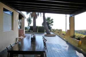 een patio met een houten tafel en stoelen en palmbomen bij 3 bedrooms villa at Sciacca 400 m away from the beach with sea view private pool and enclosed garden in Case San Marco