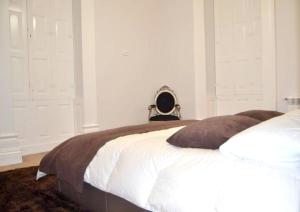 una camera da letto con un grande letto con lenzuola bianche e cuscini marroni di Welcoming Villa with Mountain View in Sobradelo da Goma a Várzea Altre 27 foto