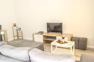 a living room with a couch and a flat screen tv at One bedroom house with shared pool enclosed garden and wifi at Atalaia 3 km away from the beach in Lourinhã