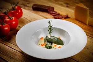 a white plate of food with tomatoes and cheese at Walserhuus Sertig in Sertig Döfli