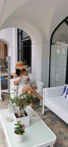 Una donna seduta su un divano bianco con un cappello di Hotel Murmann a Maratea