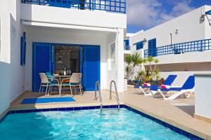 Villa mit einem Pool, einem Tisch und Stühlen in der Unterkunft Villa De La Cruz in Playa Blanca