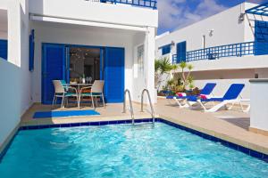 Villa mit einem Pool, einem Tisch und Stühlen in der Unterkunft Villa De La Cruz in Playa Blanca