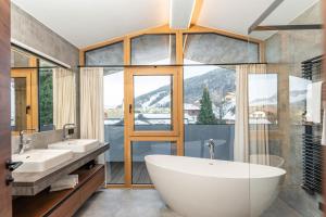 łazienka z wanną, 2 umywalkami i oknem w obiekcie Appartements Wehrhof by Schladmingurlaub w Schladming