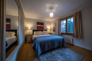 a bedroom with a bed with a blue blanket and a mirror at Chalet Christy in Nendaz