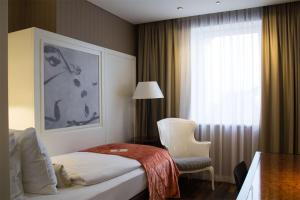 a hotel room with a bed and a chair and a window at The Harmonie Vienna, BW Premier Collection in Vienna