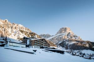 um edifício na neve com uma montanha ao fundo em Hotel Cappella em Calfosch