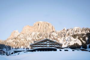 un lodge dans la neige avec une montagne en arrière-plan dans l'établissement Hotel Cappella, à Colfosco