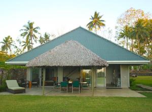 Maauga的住宿－一菲樂種植園度假屋，草屋顶房屋,配有桌椅