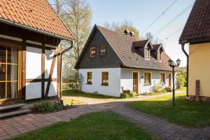 a white house with a black roof on a street at Ferienhäuser zur Schäferei in Mitwitz