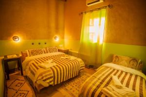 Zimmer mit 2 Betten und einem Fenster mit in der Unterkunft Takojt in Merzouga