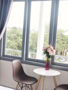 a vase of flowers on a table in front of a window at M Hotel Đà Lạt in Da Lat