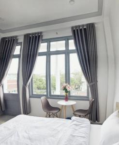 a bedroom with a bed and a table and a window at M Hotel Đà Lạt in Da Lat