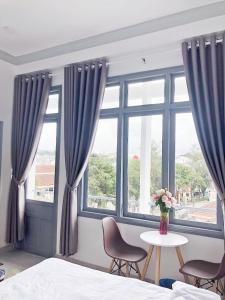 - une chambre avec un lit, une table et des fenêtres dans l'établissement M Hotel Đà Lạt, à Đà Lạt