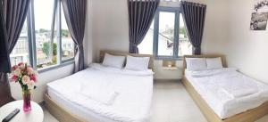 two beds in a room with two windows at M Hotel Đà Lạt in Da Lat