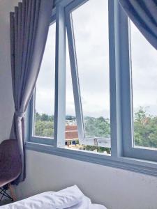 - une chambre avec trois fenêtres avec un lit et une chaise dans l'établissement M Hotel Đà Lạt, à Đà Lạt