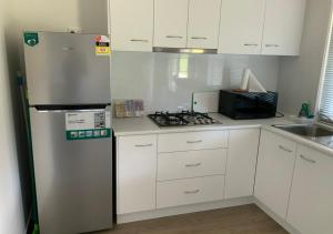 a kitchen with white cabinets and a refrigerator at Sunshine Coast retreat your own private golf course in Diddillibah