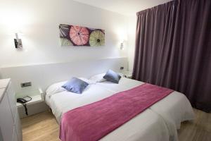 ein Schlafzimmer mit einem Bett mit lila-weißer Bettwäsche in der Unterkunft Hotel Morlans in Paguera + 16 Fotos