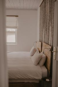 Una cama con almohadas blancas y una ventana en una habitación. en Qambathi Mountain Lodge, en Rev Estates