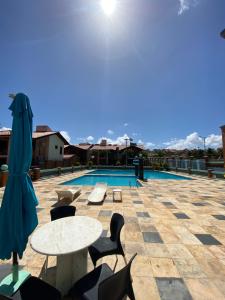 un patio con tavoli, sedie e piscina di Linda casa Porto das Dunas: 4 suítes, churrasqueira e piscina a Fortaleza