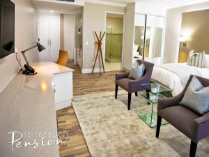 a hotel room with a bed and two chairs at Tenbergen Pension Hotel in Windhoek