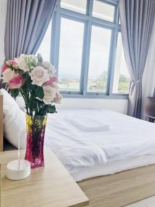 um vaso de flores em uma mesa ao lado de uma cama em M Hotel Đà Lạt em Da Lat