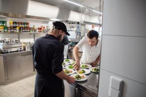 two men in a kitchen preparing plates of food at Burg Altpernstein in Untermicheldorf
