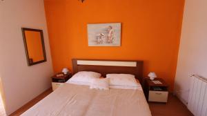 een slaapkamer met een bed met een oranje muur bij Apartments Duda in Malinska