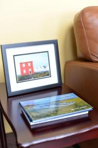 a book on a table next to a chair and a picture at Bambury's Hillside Chalets in Rocky Harbour