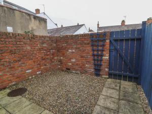 un mur en briques avec un portail bleu et une allée. dans l'établissement Armstrong Cottage, à Beverley