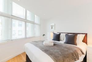 1 dormitorio blanco con 1 cama grande y ventanas en Trafalgar Square by Excel Apartments, en Londres