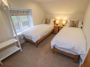 two beds in a room with a window at Shepherd's Cottage in Alford