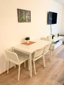 a white dining room table with white chairs and a tv at Čertovka Trojka - apartmán Harrachov in Harrachov