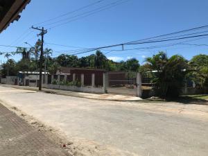 an empty street with a fence and palm trees at Farol da Barra Seca Ubatuba in Ubatuba