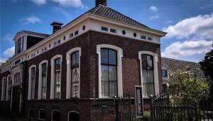 een rood bakstenen gebouw met een wit dak bij Het Weeshuis in Bolsward