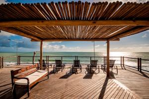 eine Holzterrasse mit Stühlen und einer Bank am Strand in der Unterkunft Porto Suítes Natal Hotel in Natal