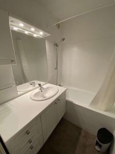 a white bathroom with a sink and a tub at Boost Your Immo Le Césier Risoul 411 in Risoul