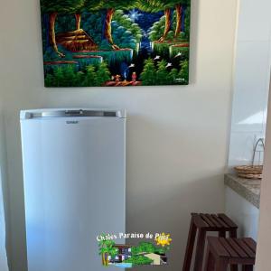 a refrigerator in a kitchen with a painting on the wall at Chalés Paraiso de Pipa in Pipa