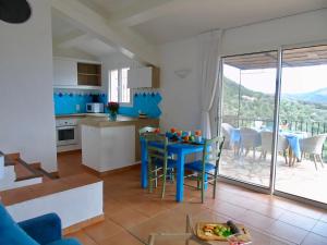 a kitchen and living room with a blue table and chairs at Résidence Belvedere de Palombaggia in Porto-Vecchio