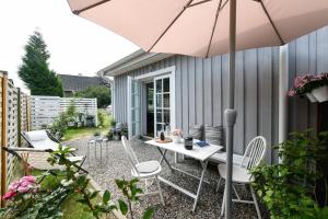 eine Terrasse mit einem Tisch, Stühlen und einem Sonnenschirm in der Unterkunft Boje 16 in Hamburg