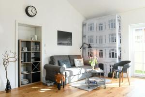 ein Wohnzimmer mit einem Sofa und einer Uhr an der Wand in der Unterkunft Boje 16 in Hamburg