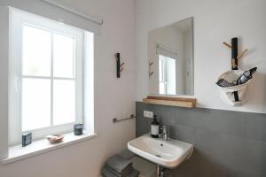 La salle de bains blanche est pourvue d'un lavabo et d'un miroir. dans l'établissement Boje 16, à Hambourg