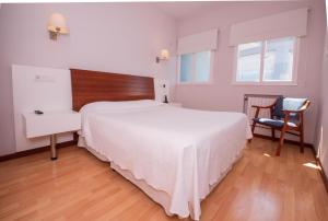 1 dormitorio con 1 cama blanca grande y 1 silla en Hotel Sablón en Llanes