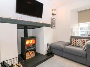 a living room with a fireplace and a tv at Rhum Cottage in Cupar
