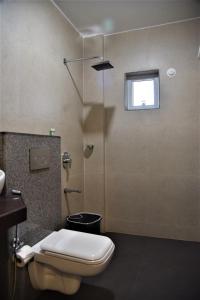 a bathroom with a toilet and a shower and a window at Aaria Hills in Arambol