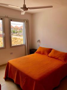 a bedroom with a large orange bed with a window at Departamentos LG in Las Grutas