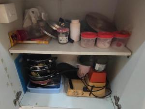 a kitchen shelf with dishes and other kitchen items at Shonar Kutir in Puri